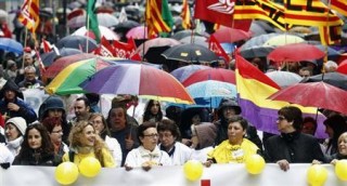 People hold umbrellas as they march with a banner during a protest against government austerity measures in Barcelona