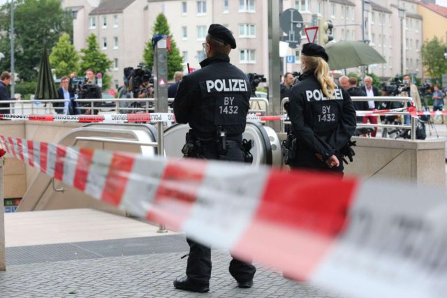 epa05437447 Police officers are seen behind a cordoned off area blocking the access to the underground station Olympia shopping center in Munich, Germany, 23 July 2016, after a shootout on the previous day. According to authorities, at least 10 people died, including the suspect, and 16 were hospitalized after a shooting at the Olympia shopping centre in Munich on 22 July 2016. By the current status of the investigations, the perpetrator, an 18-year-old German-Iranian from Munich, had apparently acted alone, police said. The motive of the incident is yet unclear. EPA/KARL-JOSEF HILDENBRAND